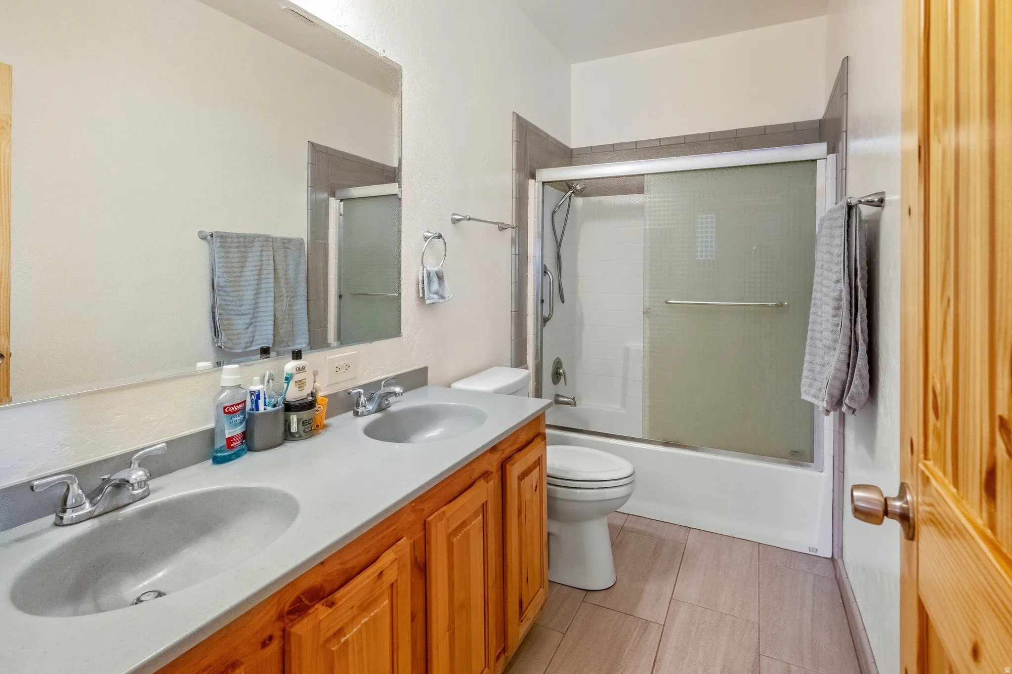 Full bathroom featuring double vanity and bath / shower combo with glass door