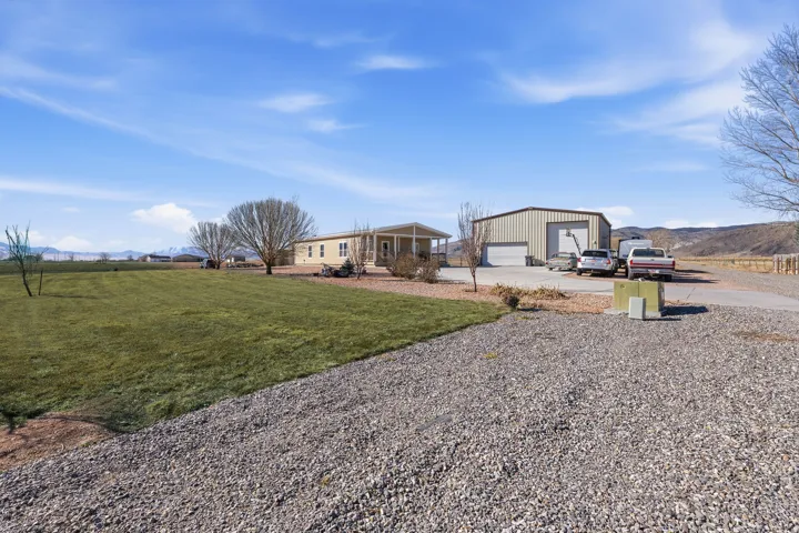 Rear view of property featuring a mountain view, a garage, covered porch, a yard, and driveway