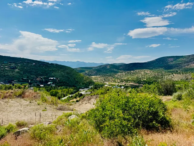Expansive mountain landscape featuring varied terrain, distant peaks, and a valley with scattered structures