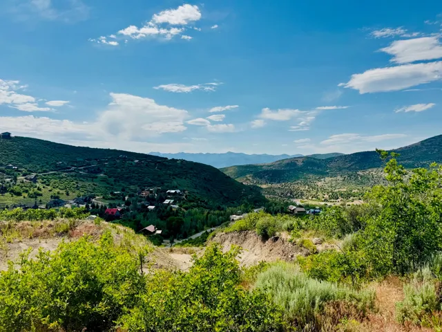 Expansive mountainous landscape featuring distant peaks and a vibrant blue sky with scattered clouds