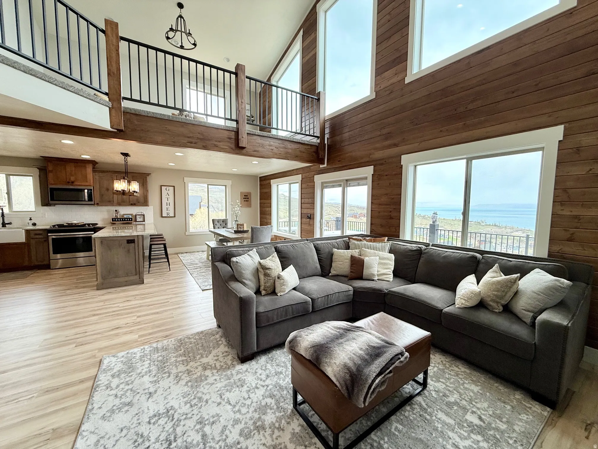 Living room featuring a chandelier, wooden walls, light wood-style flooring, a high ceiling, and a water view