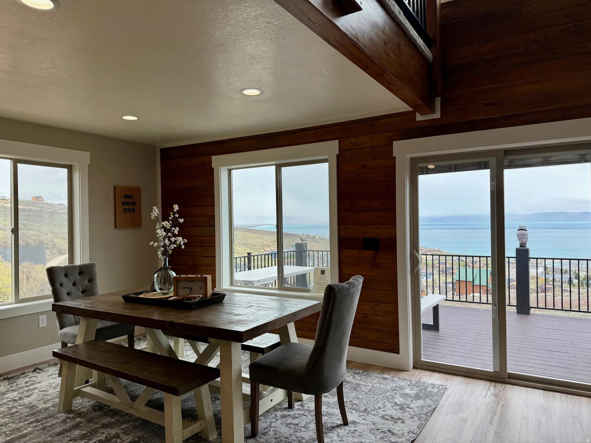 Dining space with wood walls, a water view, a textured ceiling, light wood-style floors, and recessed lighting
