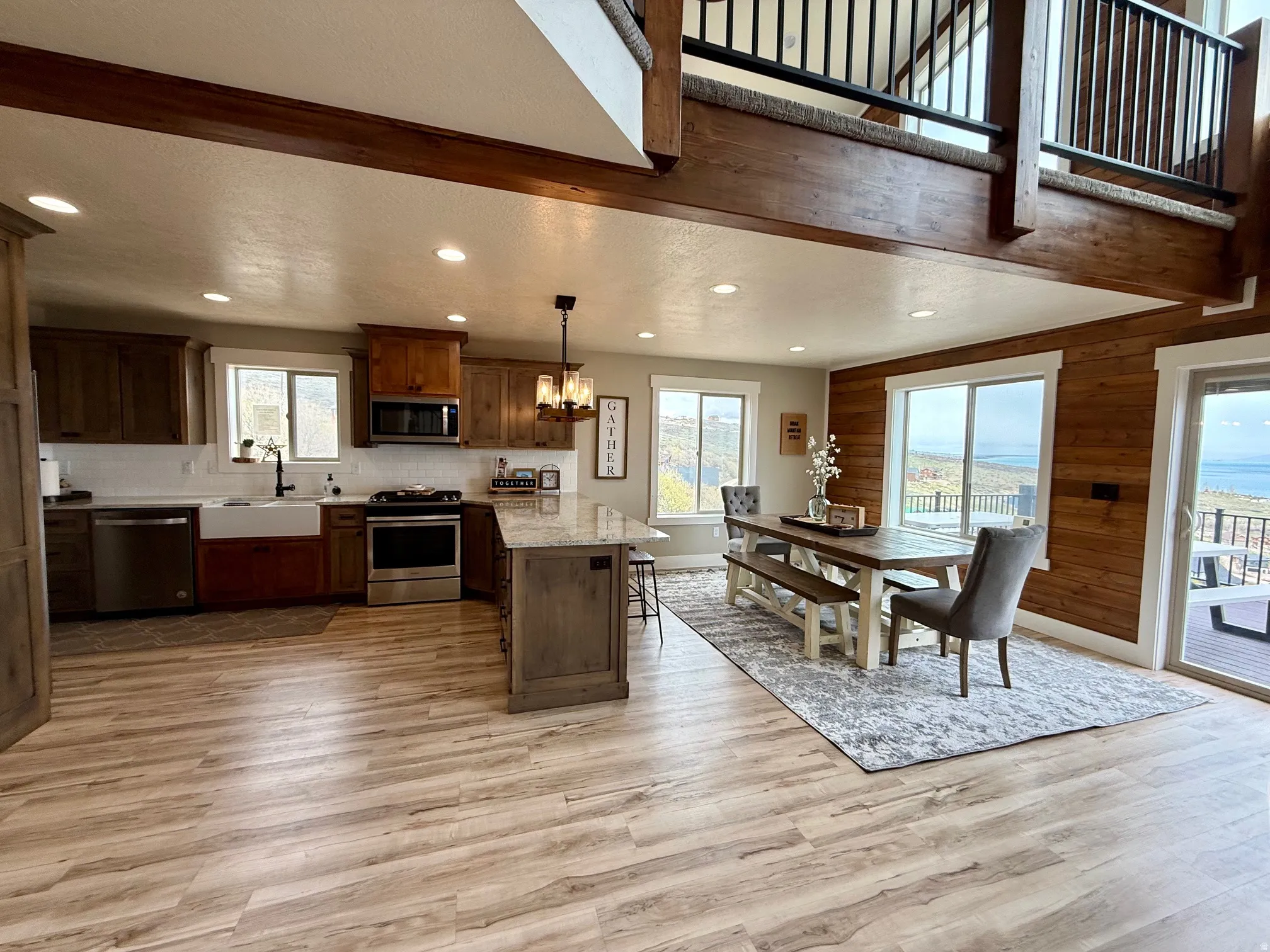Kitchen featuring a peninsula, stainless steel appliances, suspended lighting, light wood-style flooring, and wooden walls