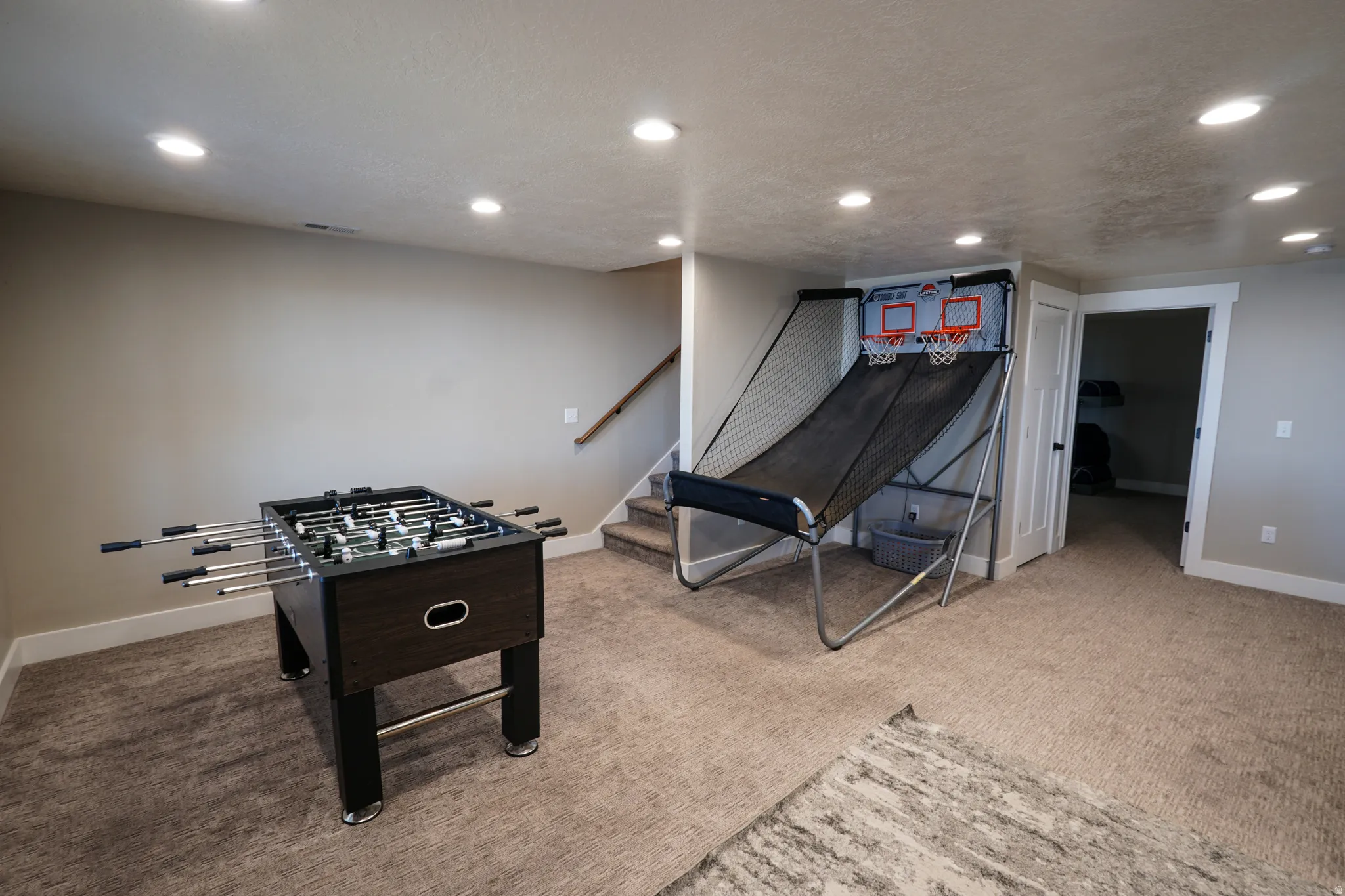 Game room with recessed lighting, light colored carpet, and a textured ceiling