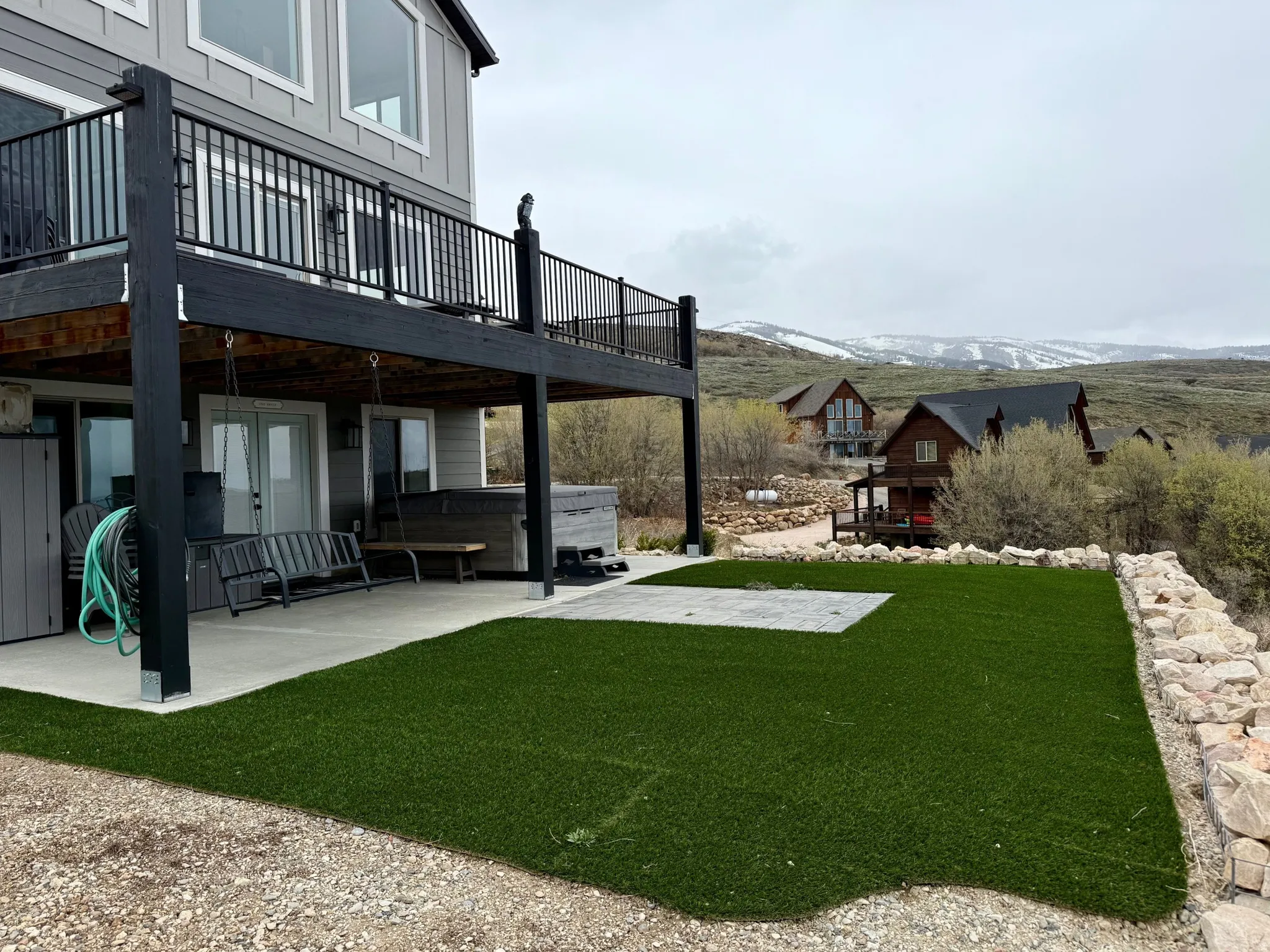 View of grassy yard with a patio, a hot tub, and a deck with mountain view