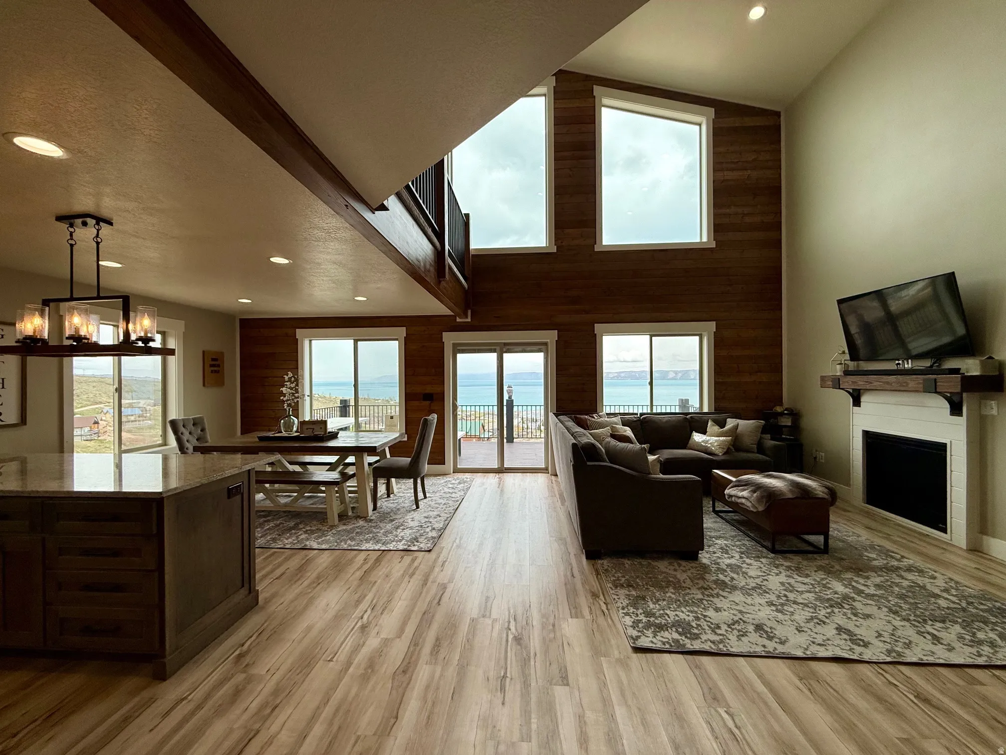 Living room featuring light wood-style flooring, a fireplace, wood walls, vaulted ceiling, and a chandelier