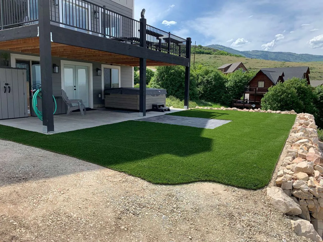 View of grassy yard featuring a hot tub, a patio area, a deck with mountain view, and french doors