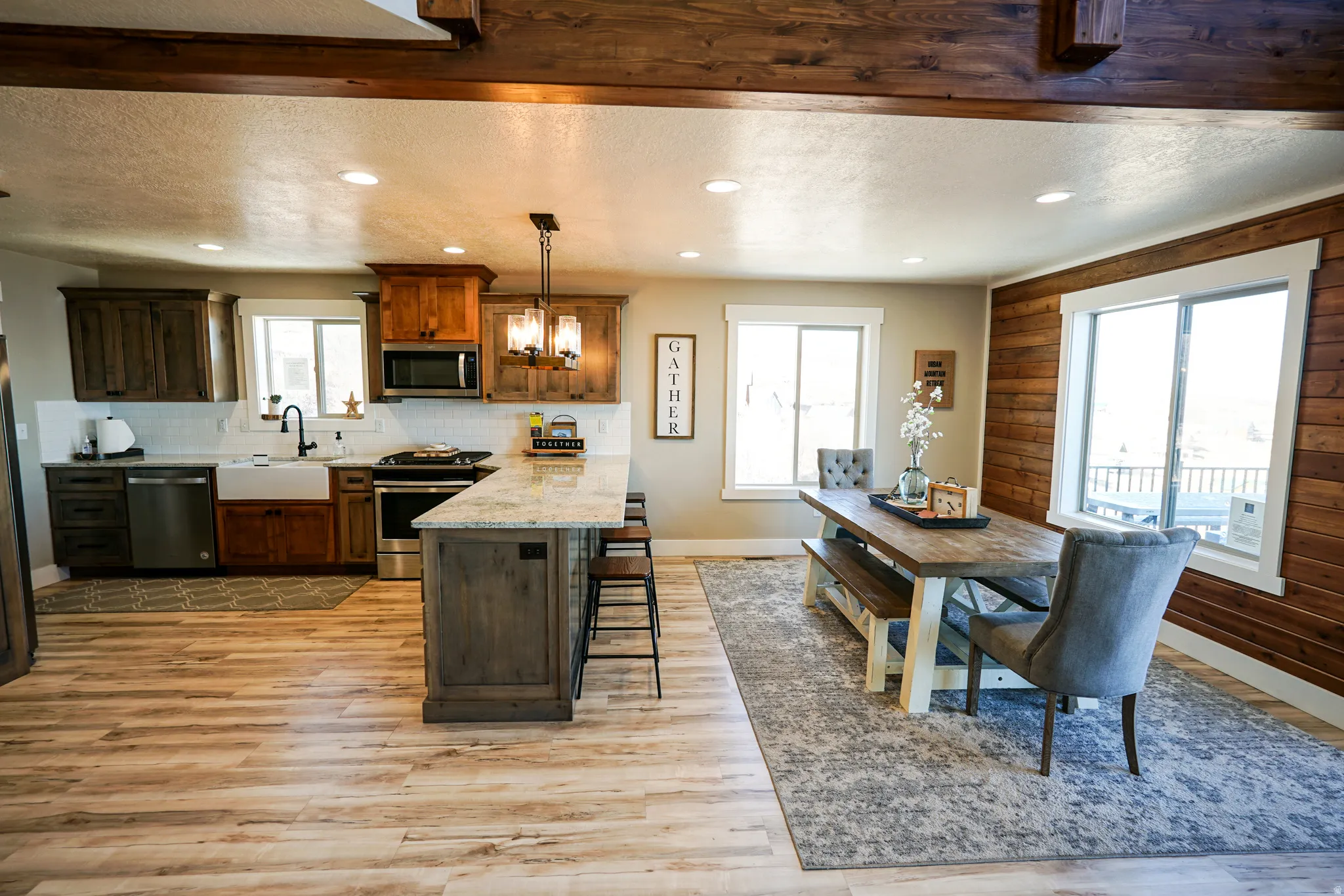 Kitchen featuring stainless steel appliances, light stone counters, a peninsula, a breakfast bar area, and light wood-type flooring