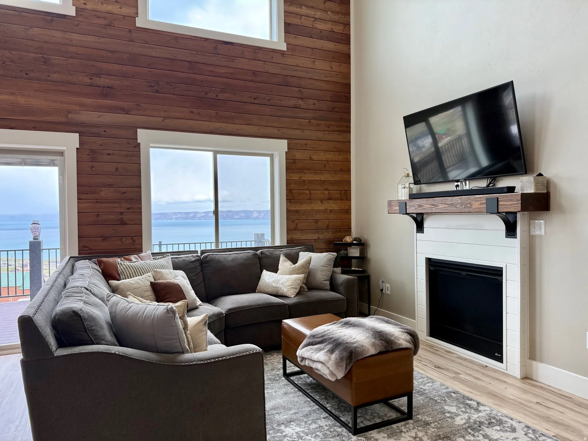 Living area featuring wooden walls, light wood-style floors, a high ceiling, and a fireplace