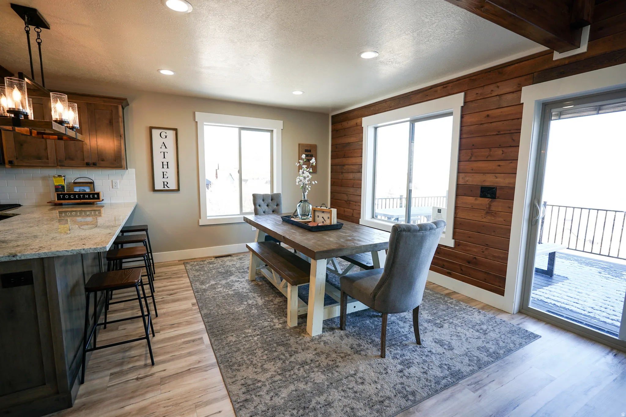 Dining area featuring light wood-style floors, wooden walls, a chandelier, and a textured ceiling