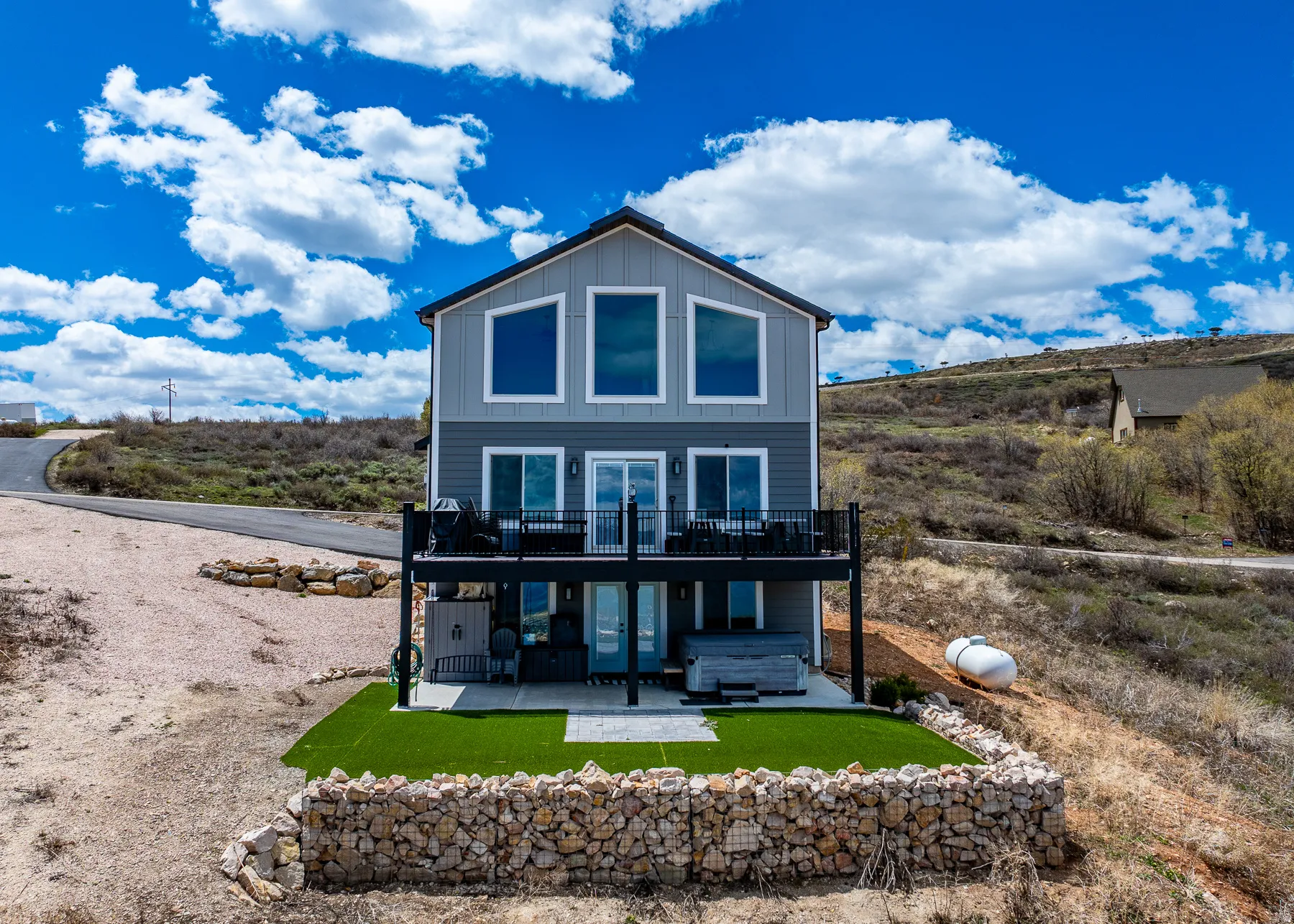 Back of property featuring board and batten siding, a patio area, a wooden deck, and a yard