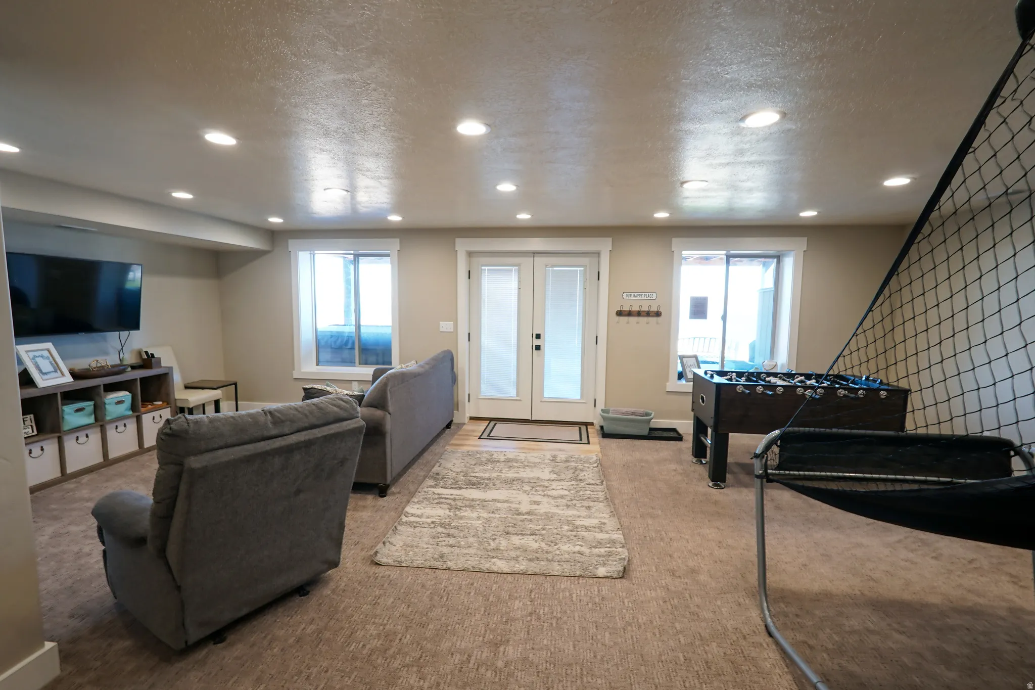 Carpeted living room with a textured ceiling, recessed lighting, and french doors