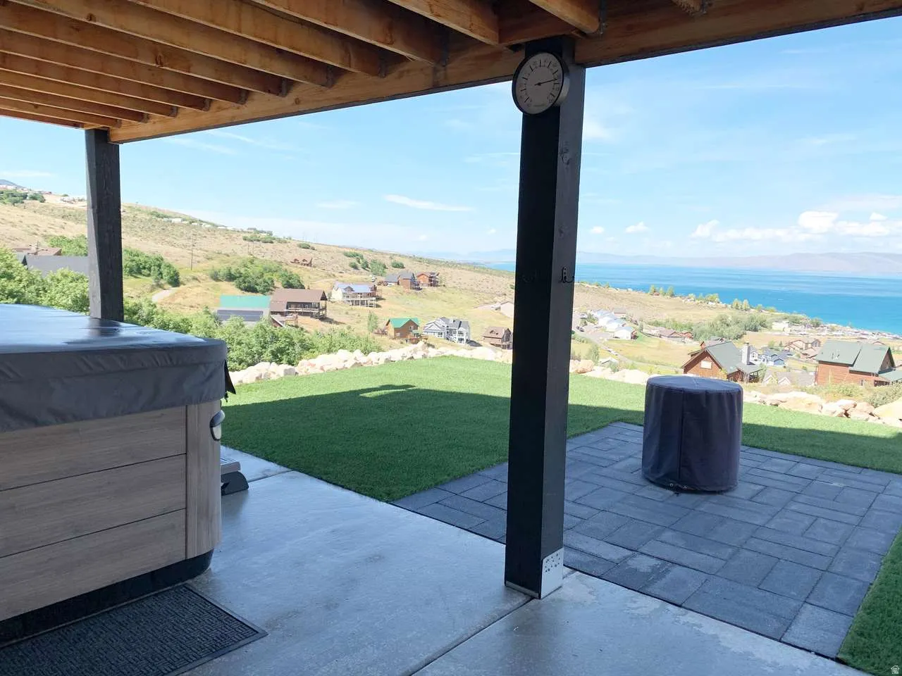View of patio with a water view and a hot tub