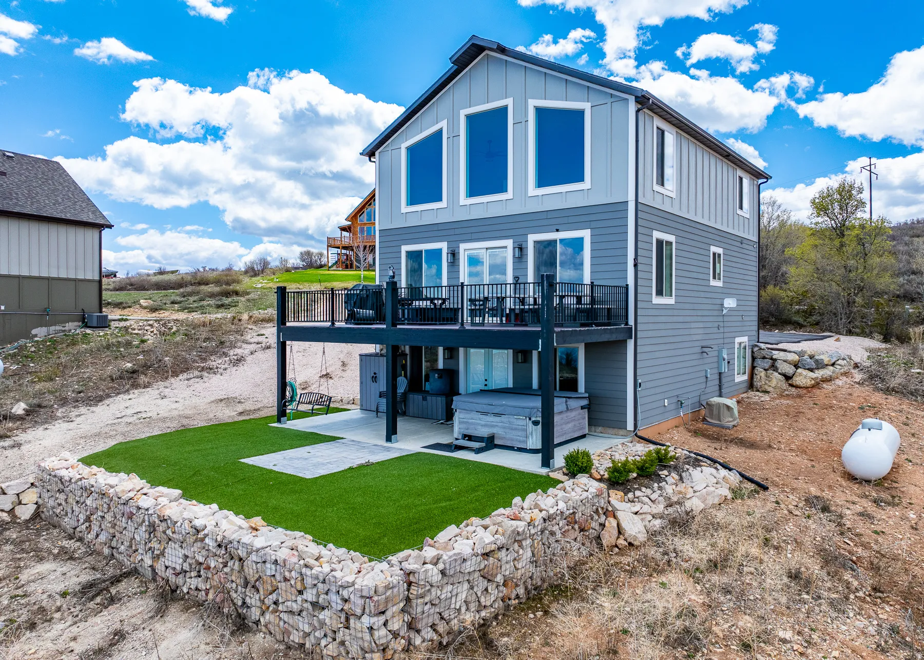 Rear view of property with a patio area, board and batten siding, a hot tub, a wooden deck, and a yard