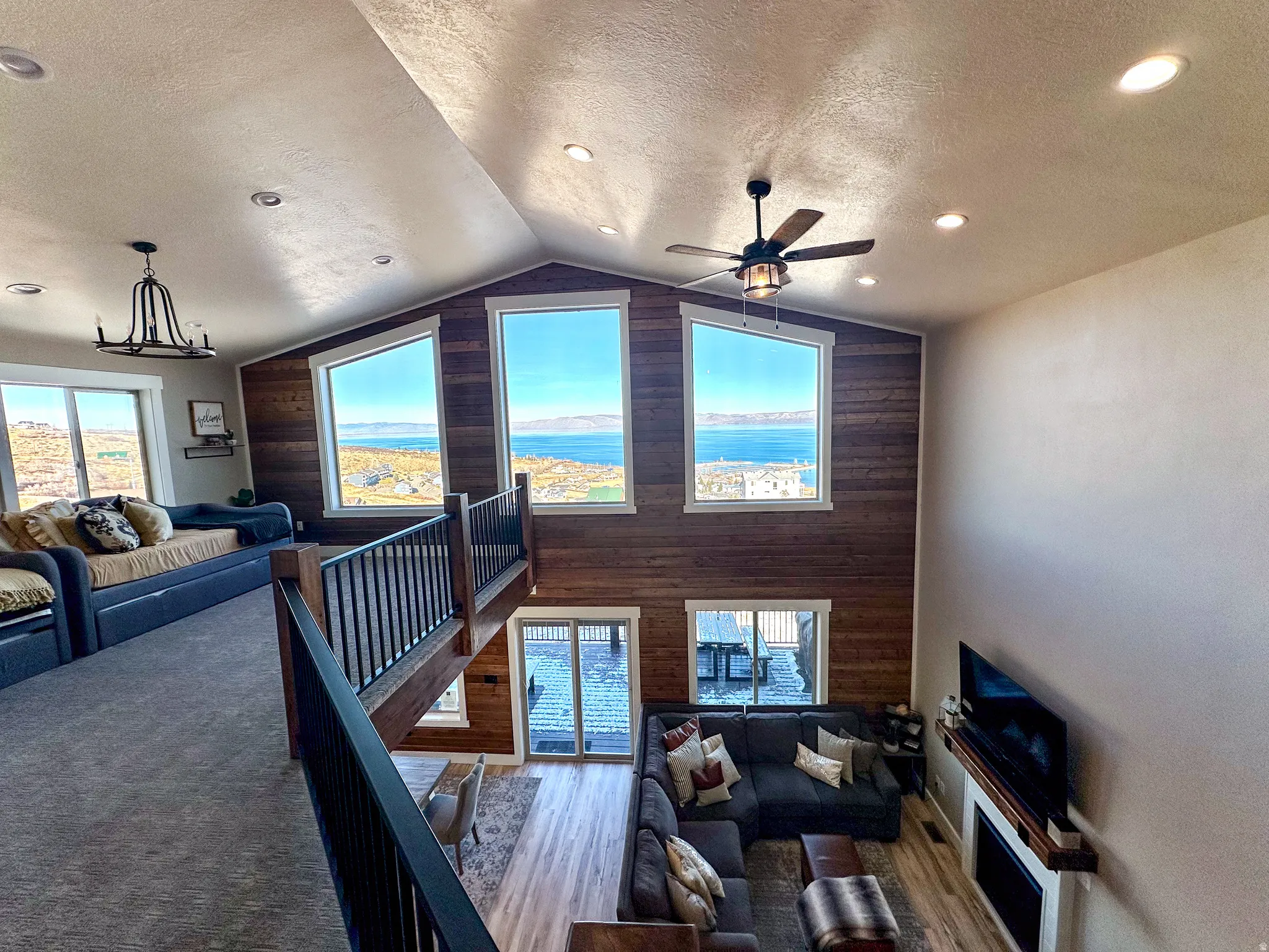 Living area featuring ceiling fan, wood finished floors, a high textured ceiling, wood walls, and recessed lighting