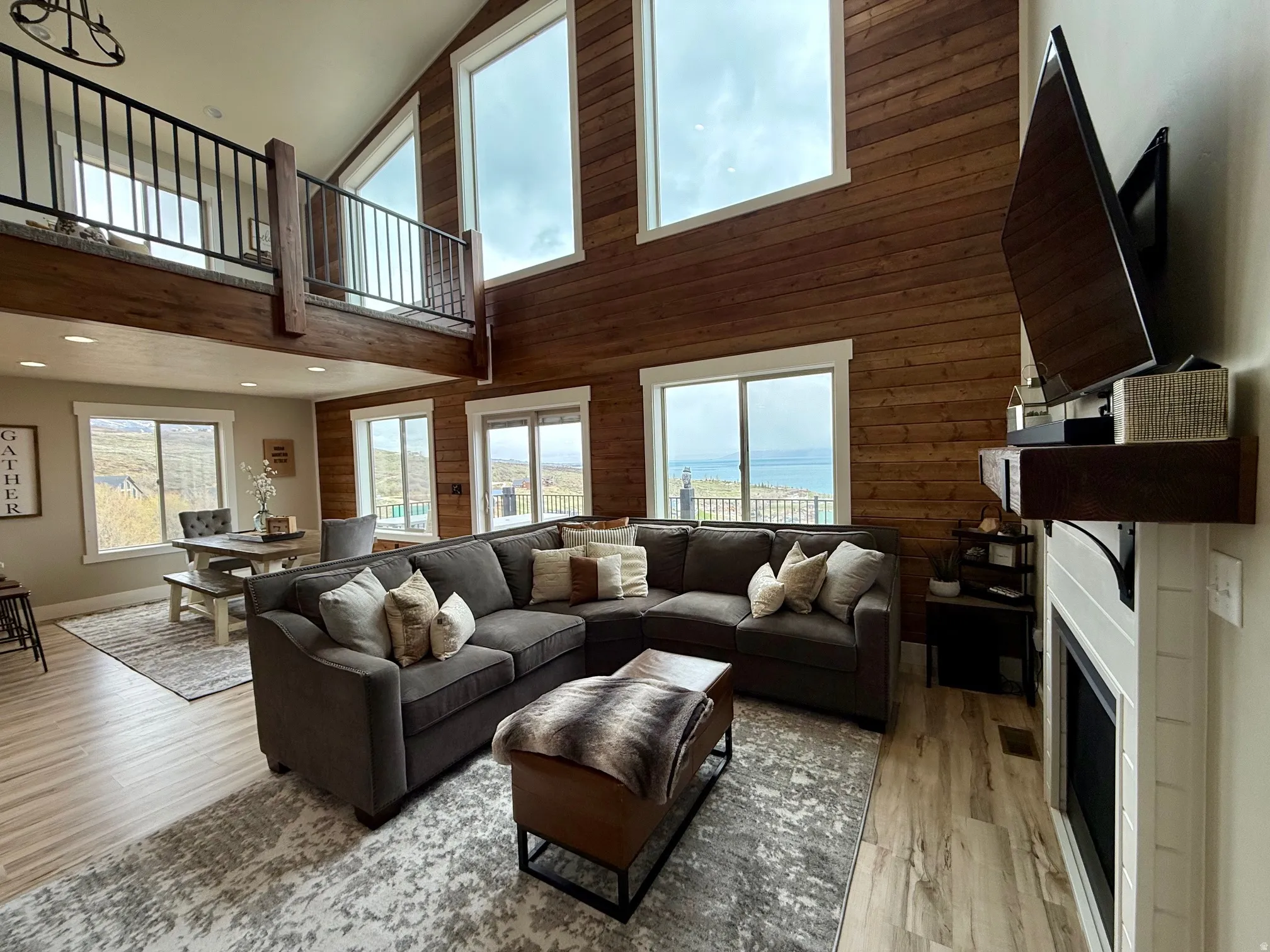 Living room featuring wood walls, a fireplace, healthy amount of natural light, light wood finished floors, and lofted ceiling