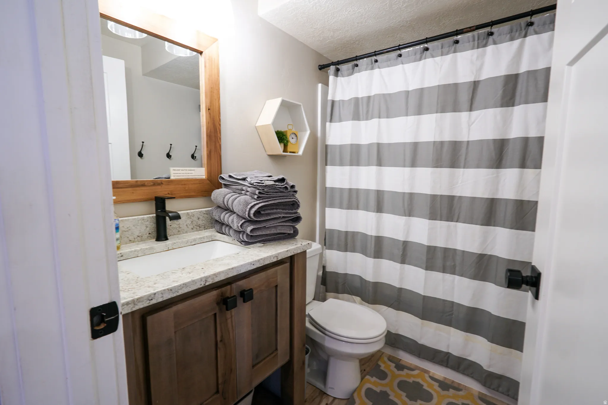 Full bath featuring curtained shower, vanity, and a textured ceiling