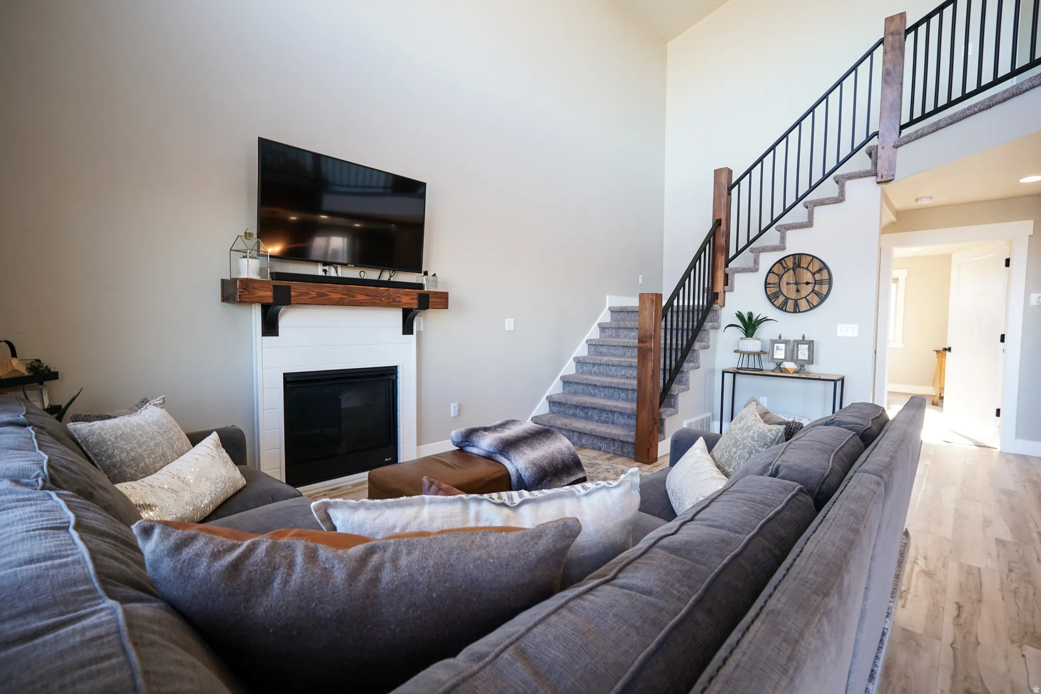 Living room featuring a high ceiling, light wood-type flooring, and a large fireplace