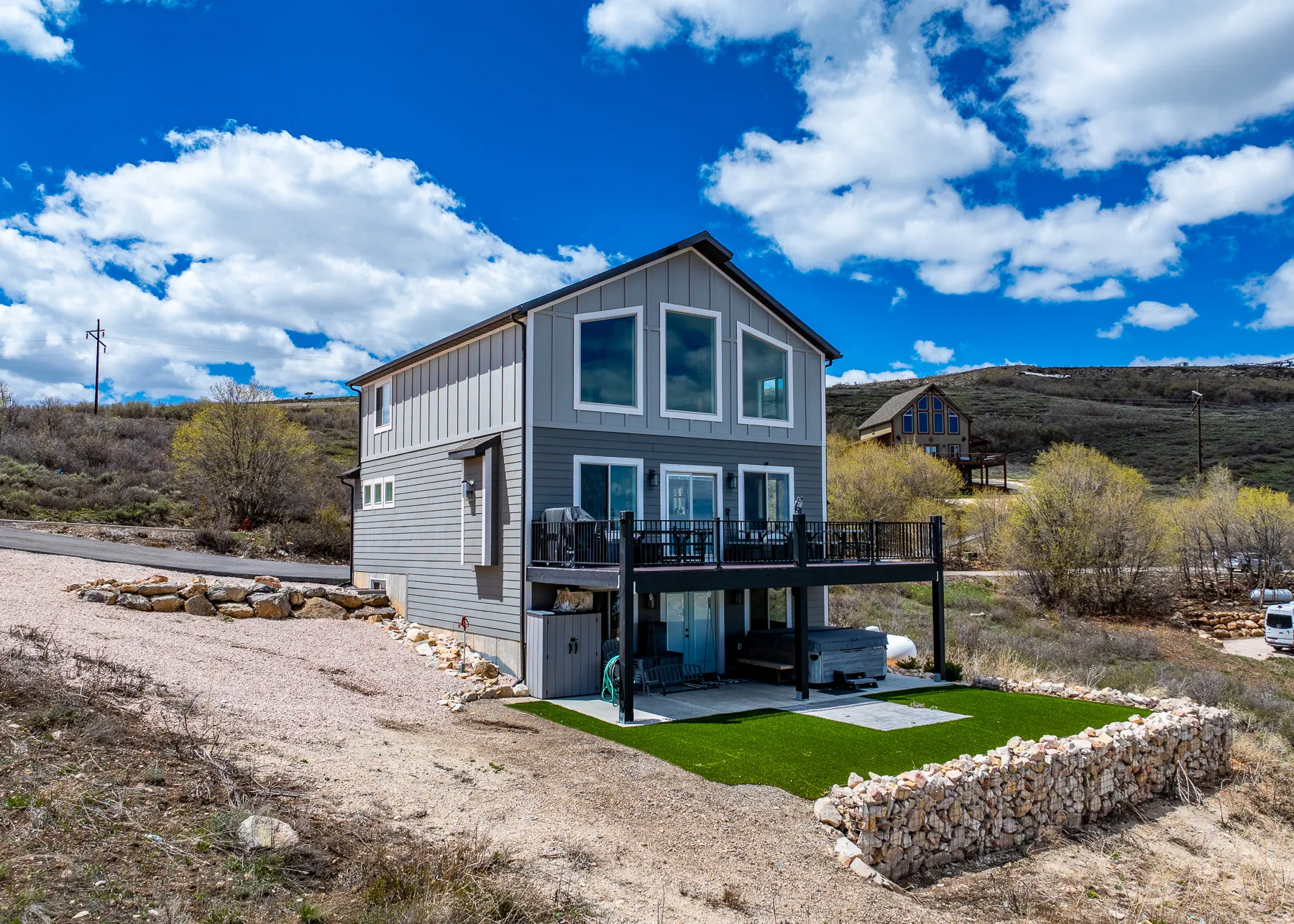 Rear view of house with board and batten siding, a deck, and a hot tub