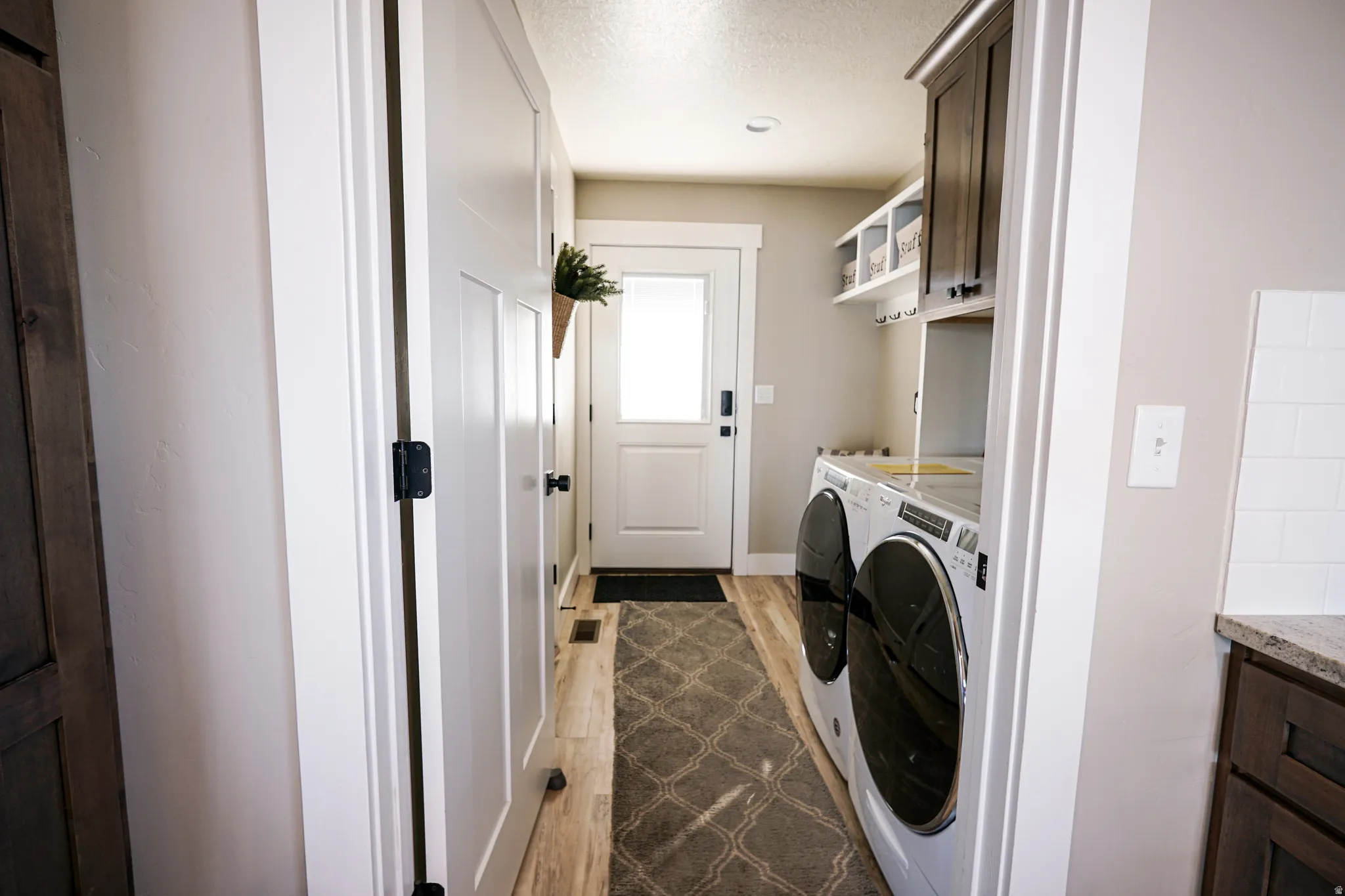 Laundry room with dark wood-type flooring, washing machine and clothes dryer, a textured ceiling, and cabinet space
