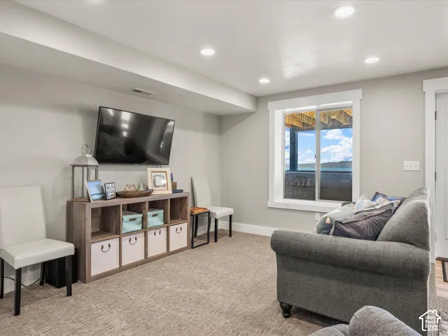 Recessed lighting illuminates a neutral-toned room with carpet flooring