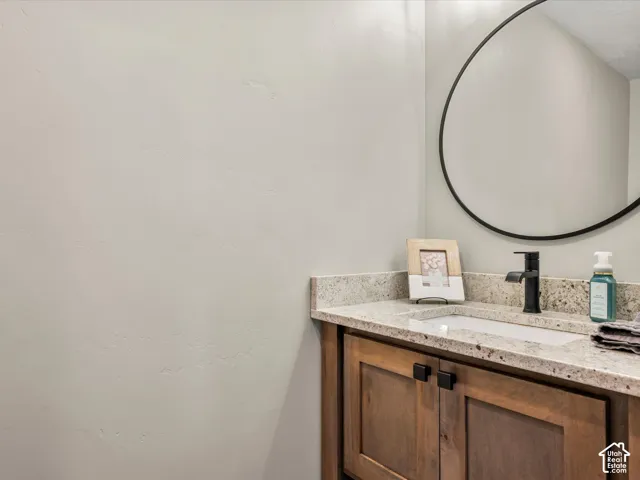 Granite-finish countertop with an integrated rectangular sink, matte black faucet, and wood-finish cabinetry with black hardware