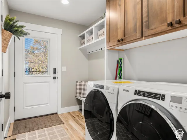 Laundry area featuring wood-finish flooring, built-in wooden cabinetry, white shelving with hooks, and a built-in bench