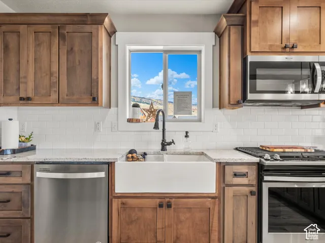 Kitchen featuring wood cabinetry, white subway tile backsplash, a stainless steel dishwasher, and a white farmhouse sink