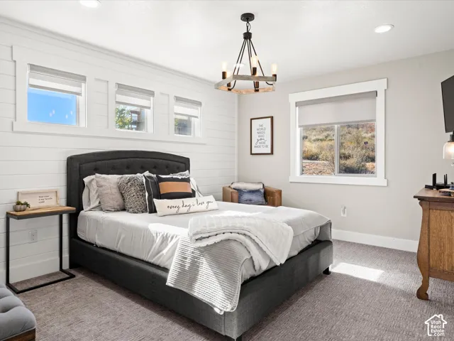 White shiplap wall treatment, recessed lighting, and a chandelier with a wood-finish accent