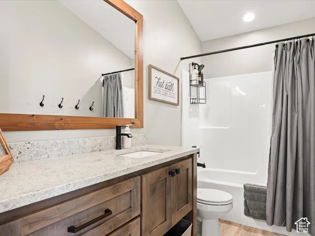 Vanity with wood-finish cabinetry, light-toned countertop, and undermount sink