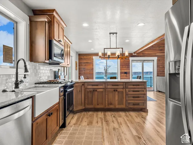 Kitchen featuring wood cabinetry, stainless steel appliances, a farmhouse sink, white subway tile backsplash, and a central island with granite countertops