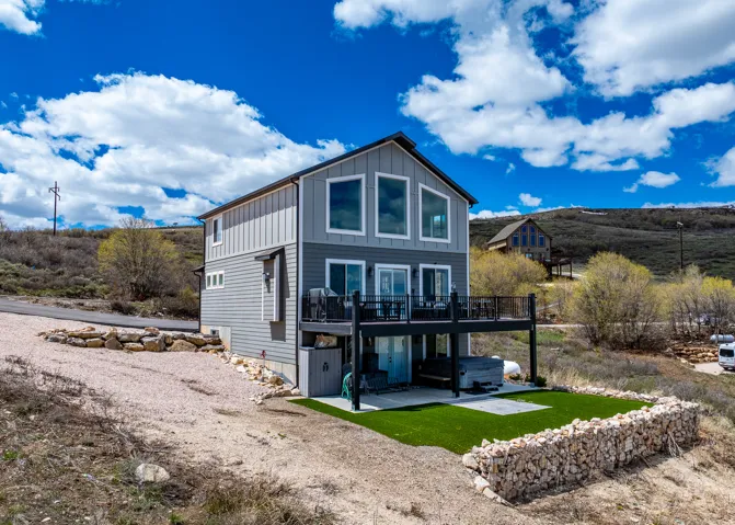 View of house with board and batten siding, a deck, and a hot tub