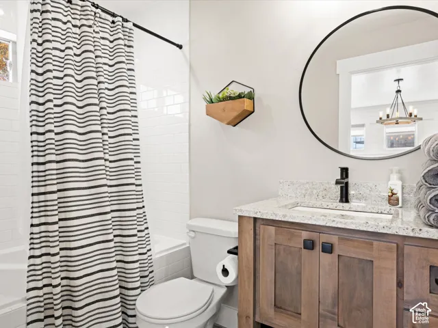 Bathroom featuring white subway tile surround, a built-in tub, wood-finish vanity with stone countertop, and a circular mirror