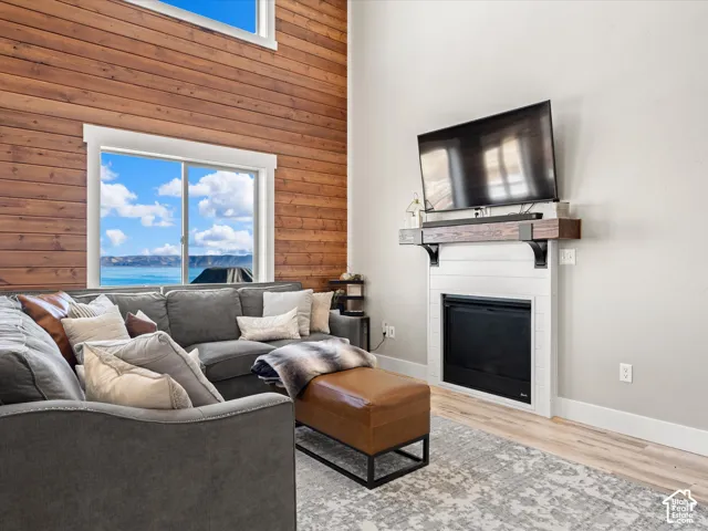 Wood-finish accent wall with large picture windows, integrated fireplace with white shiplap surround, and wood-finish mantel with black brackets