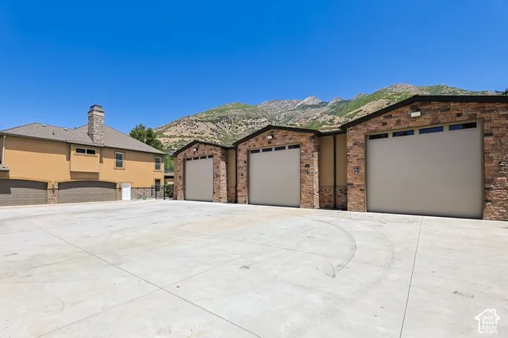 Expansive concrete driveway including main home 4 car garage & multiple garage bays featuring brick and stone exterior finishes