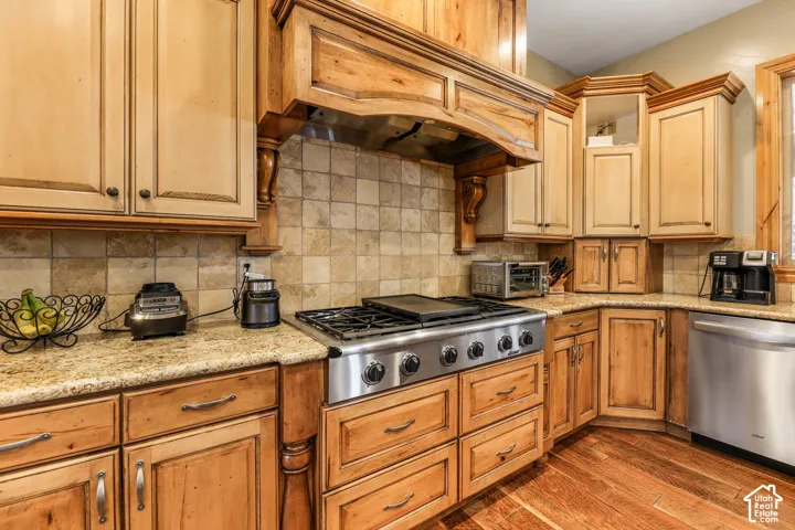 Kitchen with stainless steel appliances, light stone countertops, dark wood finished floors, and backsplash