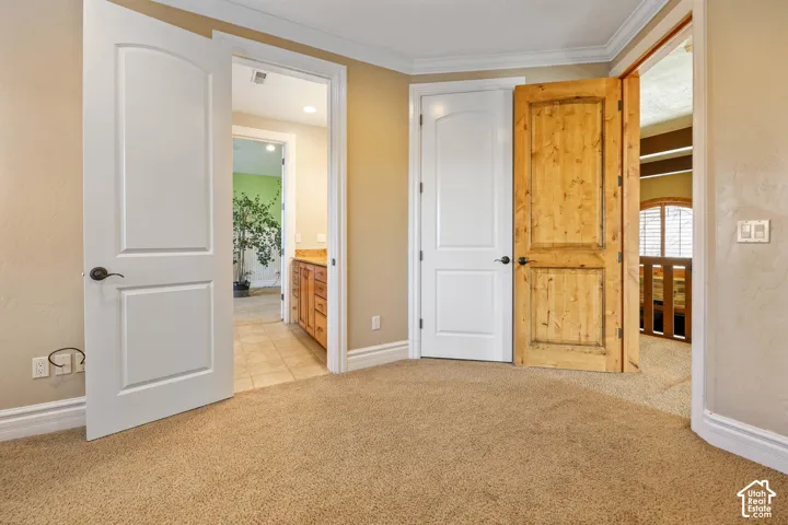 Unfurnished bedroom with light colored carpet and ensuite bath