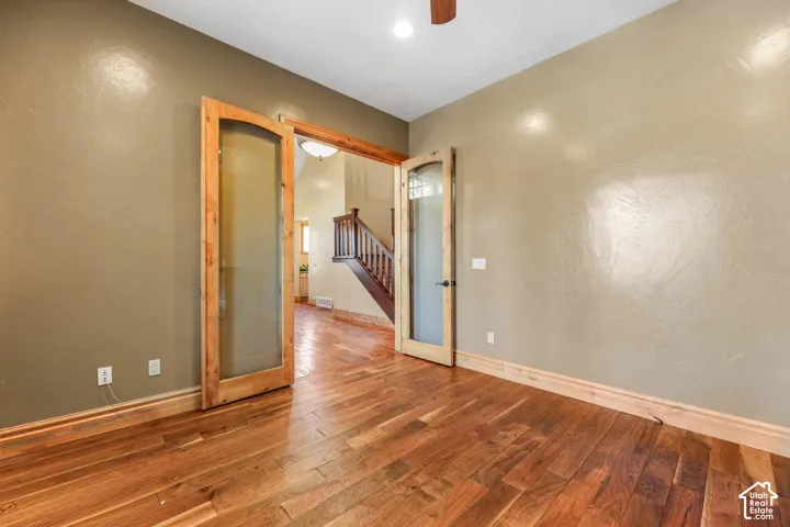 Unfurnished room featuring hardwood / wood-style floors, french doors, and ceiling fan