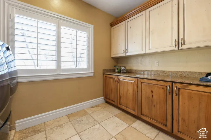 Kitchen featuring dark stone counters, wood finish cabinetry, and stone tile floors