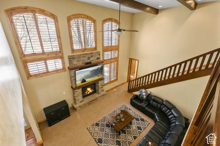 Carpeted living room with a fireplace and ceiling fan