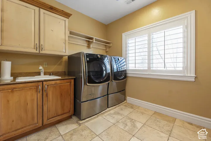 Laundry room with cabinet space, washing machine and clothes dryer, and light stone finish flooring