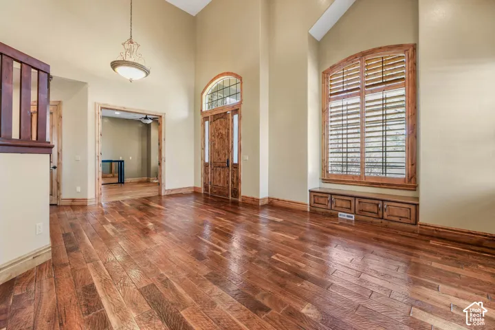 Foyer with dark wood-style floors, a high ceiling, and ceiling fan