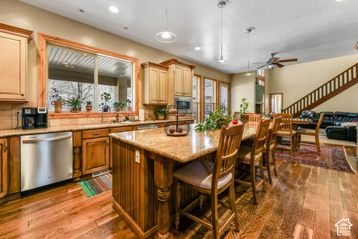 Kitchen with stainless steel appliances, backsplash, open floor plan, and pendant lighting