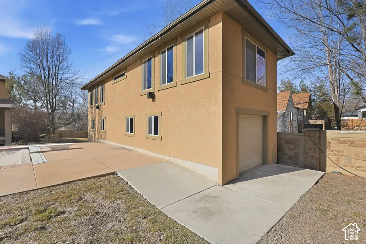 View of property exterior of secondary building (pool House) with an attached garage, stucco siding, and a gate