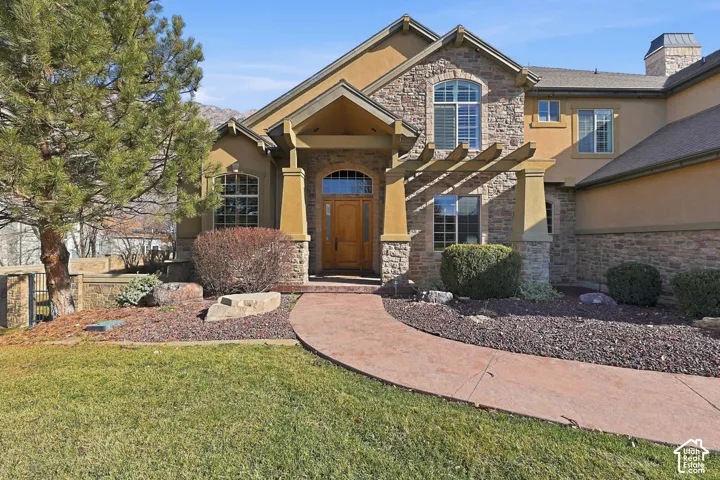 Craftsman house with stone siding, stucco siding, a front lawn, and a chimney