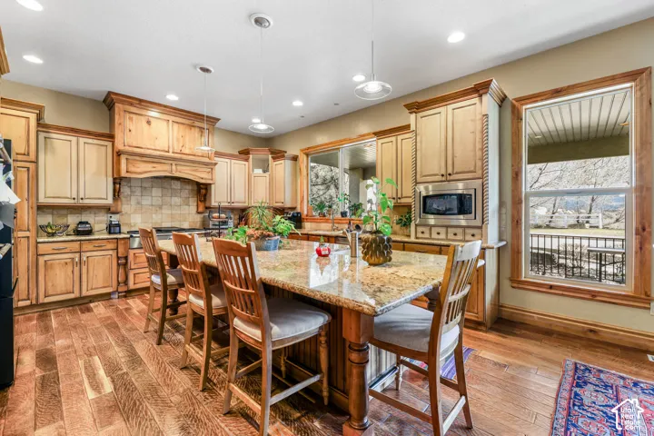 Kitchen featuring a kitchen breakfast bar, a center island, light wood-style flooring, pendant lighting, and light stone countertops