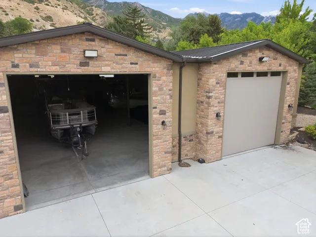 Stone veneer exterior with two garage bays, concrete driveway, and black metal roofing