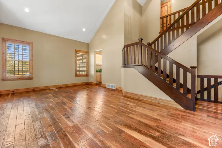 Unfurnished living room featuring light wood-style floors, lofted ceiling, and recessed lighting