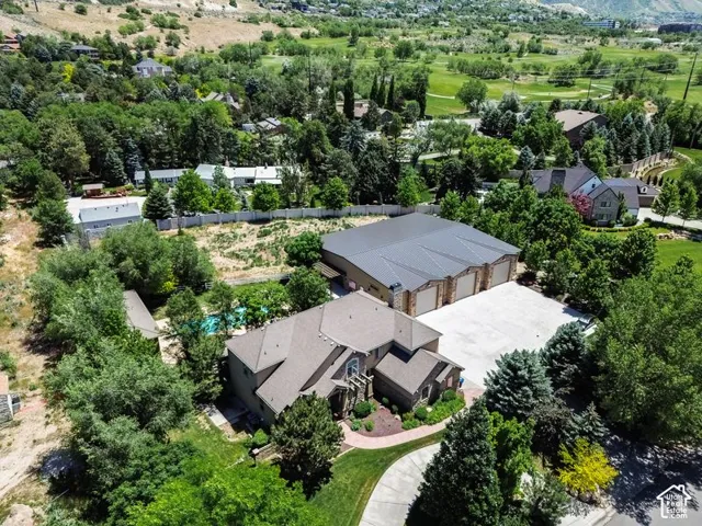 Aerial view showcasing a contemporary residence nestled on expansive grounds surrounded by mature landscaping and towering trees