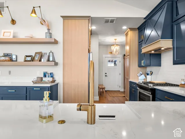 Kitchen featuring white countertops, blue cabinetry, wood-finish cabinetry, a brass-toned faucet, and subway tile backsplash